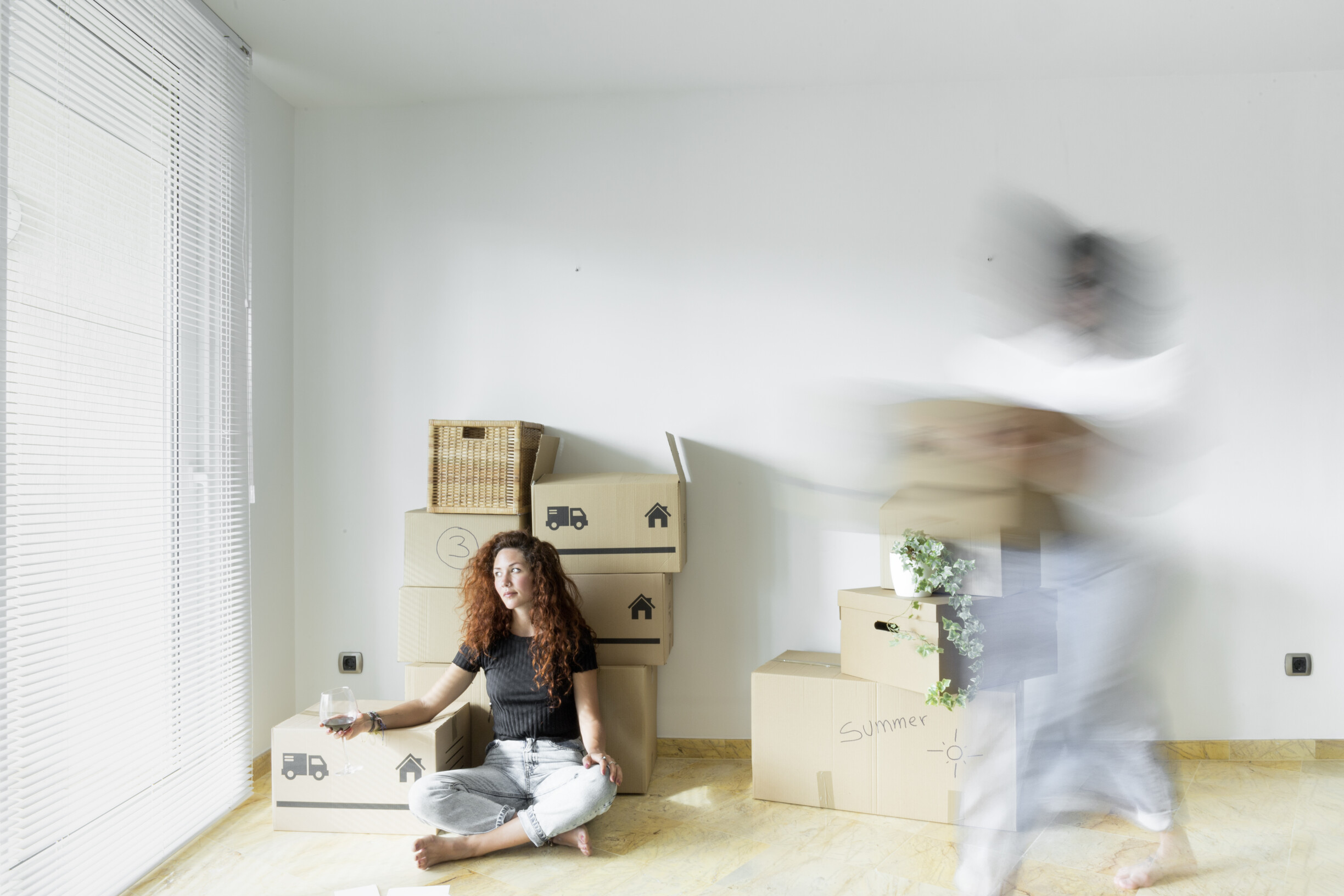 young-woman-sitting-in-new-home-with-glass-of-red-2023-11-27-05-35-44-utc.jpg